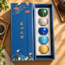 Juego de té de cinco tazas craqueladas en caja de presentación azul, ambientado sobre madera con luz natural.